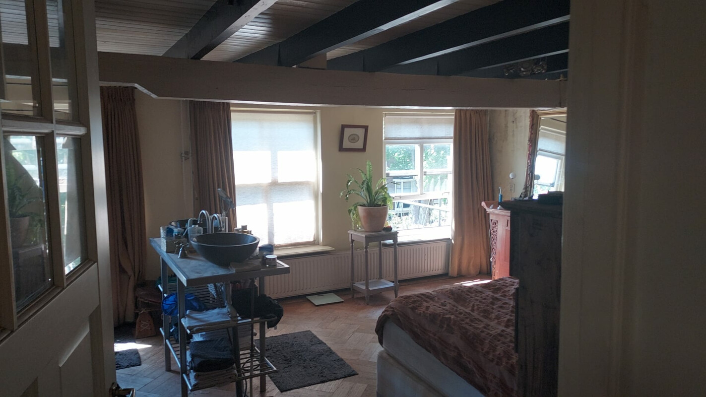 Mooie sfeervolle kamer met uitzicht op bomen en groen van tuinen.